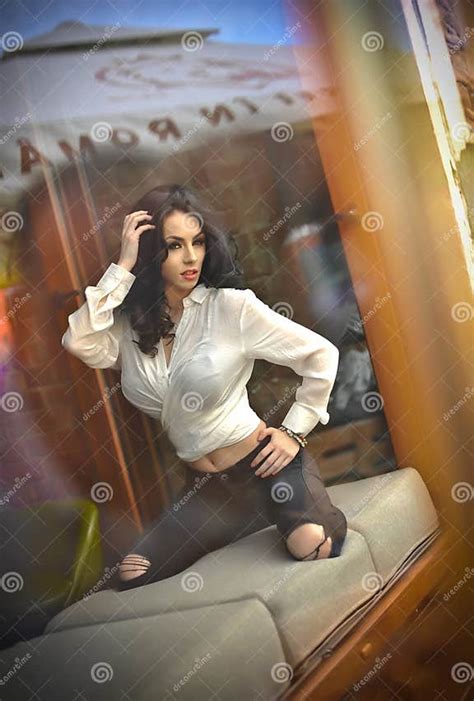 Attractive Brunette In White Tight Fit Shirt And Black Ripped Jeans
