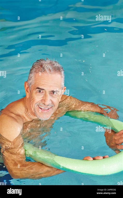 Senior Man Doing Aqua Fitness In The Swimming Pool With A Swimming