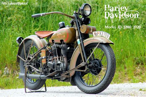 An Old Motorcycle Is Parked On The Side Of The Road With Grass In The