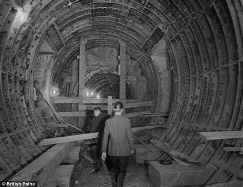 Two Men Are Walking Through A Tunnel With Wooden Beams On The Floor And