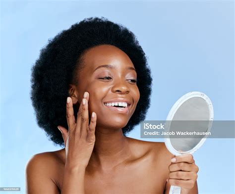 black woman face and beauty looking in mirror and natural cosmetics with glow isolated on blue