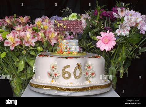 A 60th Birthday Cake With Wishing Well On Top And Cut Flowers In The