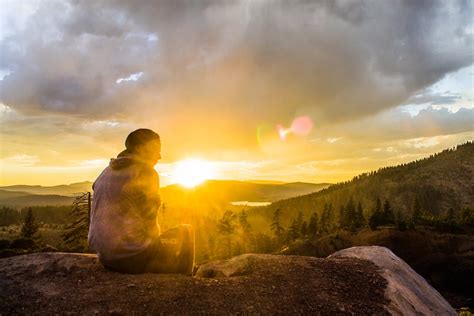 Person Sitting On Stone Facing Sunset · Free Stock Photo