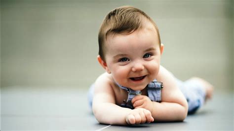 Cute Smiley Baby Is Lying Down On Floor Wearing Light Blue