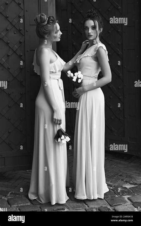 two beautiful bridesmaids girls blonde and brunette ladies wearing elegant full length light