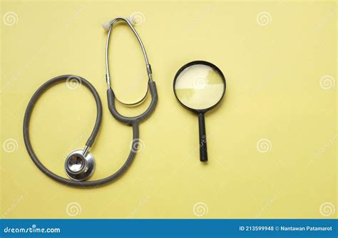 Stethoscope And Magnifying Glass On Yellow Doctor`s Desk Health And