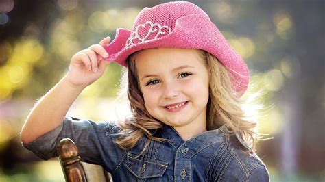 Cute Smiley Little Girl Is Wearing Jeans Shirt And Pink Hat Sitting On