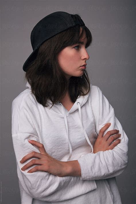 teen girl in cap with arms folded looking away with indifference by stocksy contributor danil