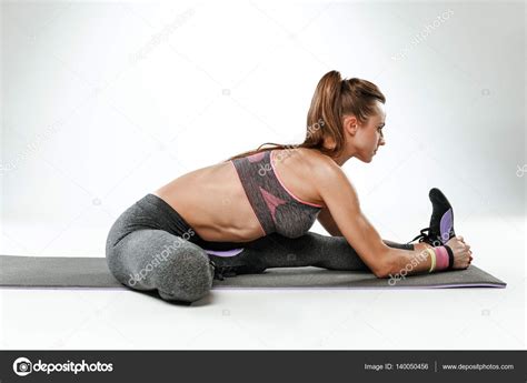 Beautiful Slim Brunette Doing Some Stretching Exercises In A Gym Stock