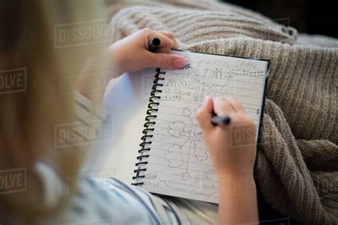 High Angle View Of Girl Writing In Diary While Sitting At Home Stock