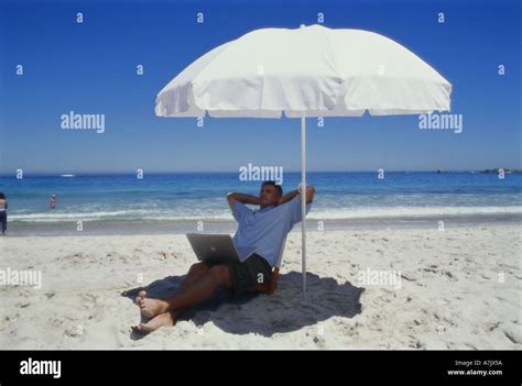 Young Man Lying Under An Umbrella On The Beach Stock Photo Alamy
