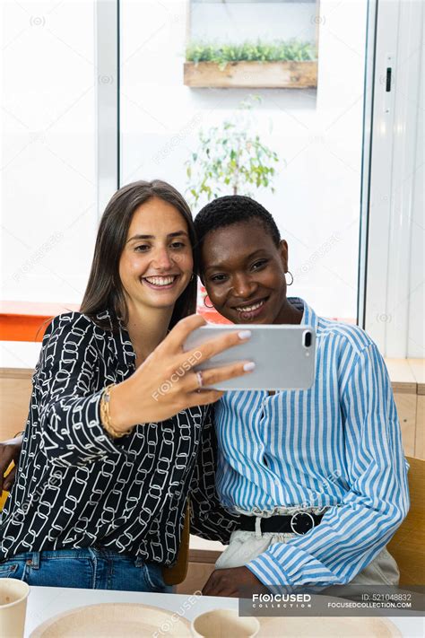 Cheerful Multiracial Female Colleagues Taking Self Portrait On Smartphone While Having Lunch