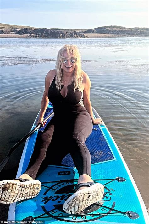 Carol Vorderman Squeezes Her Curves Into A Busty Black Wetsuit As She Enjoys Paddleboarding