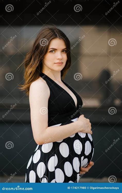 A Beautiful Stylish Young Pregnant Woman In A Black Dress With White