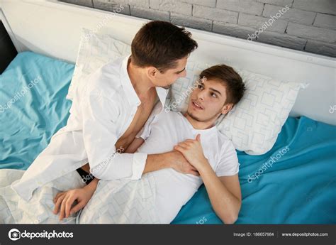 Jeune couple gay couché dans le lit à la maison image libre de droit par belchonock