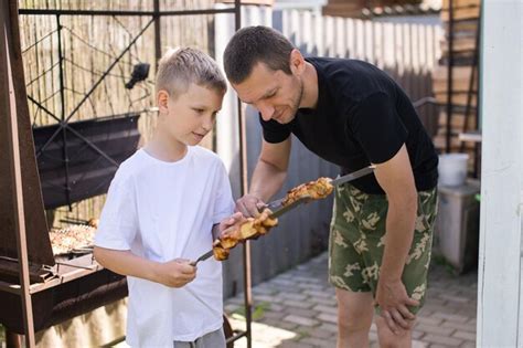 Premium Photo Funny Dad And Son Try Grilled Meat