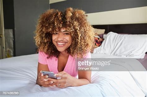 Smiling Black Woman Laying On Bed Texting On Cell Phone Photo Getty