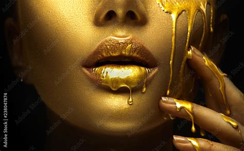 Foto De Golden Paint Smudges Drips From The Face Lips And Hand Golden Liquid Drops On Beautiful
