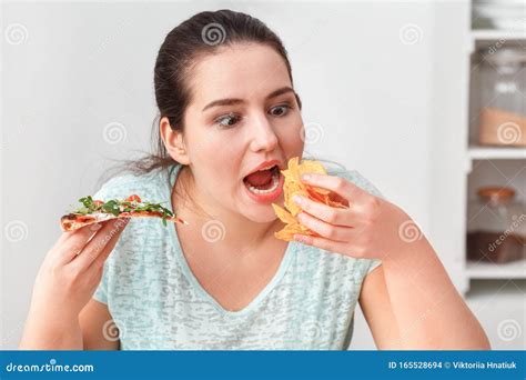 Binge Eating Chubby Mädchen Sitzt Am Küchentisch Und Isst Pizza Und Pommes Frites In Der Nähe