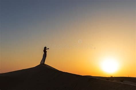 Silhouette Of A Woman Staying On The Sand Dune Looking At Sunset Stock