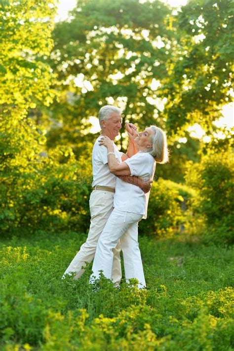 Happy Beautiful Senior Couple Dancing In Summer Park Stock Image