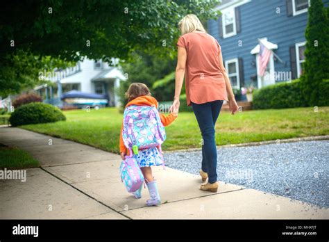 Mid Adult Woman Walking With Daughter On Suburban Sidewalk Rear View