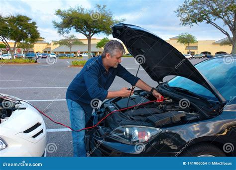 Man Jump Starting A Car With Jumper Cables Stock Photo Image Of Mall