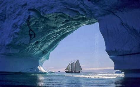 Arctic Sailing Sailboat Seen Through Huge Iceberg Cave In Greenland