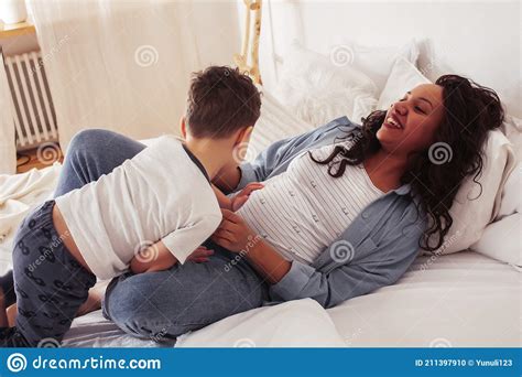 Young Pretty African Americam Mother With Son In Bed At Morning Playing
