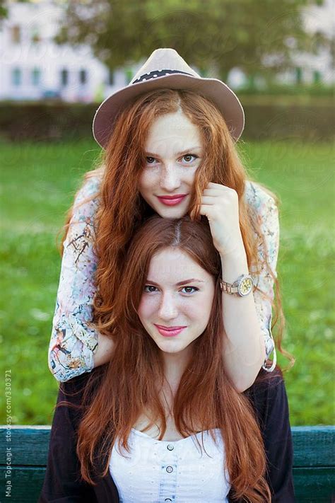 two beautiful redheaded sisters looking in camera on a sunny day by maja topčagić redheads