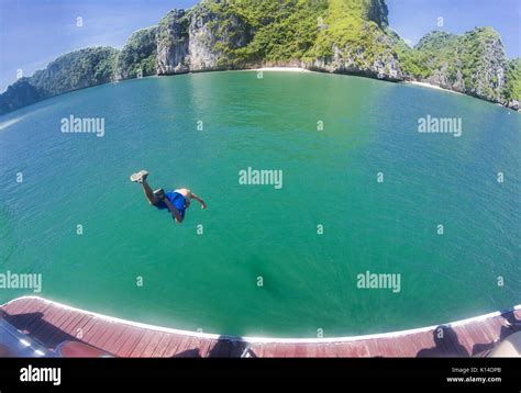 Man Jumping Into Water From A Cruise Boat On A Sunny Day In Ha Long Bay