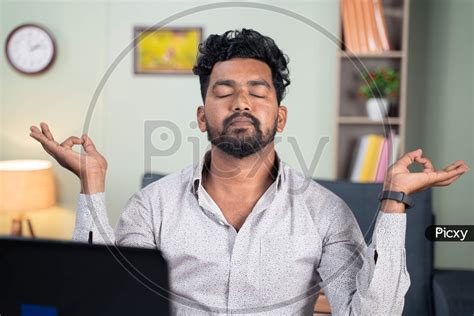 Image Of Young Man Meditating At Home Due To Work Pressure Or Stress Concept Of Taking Break