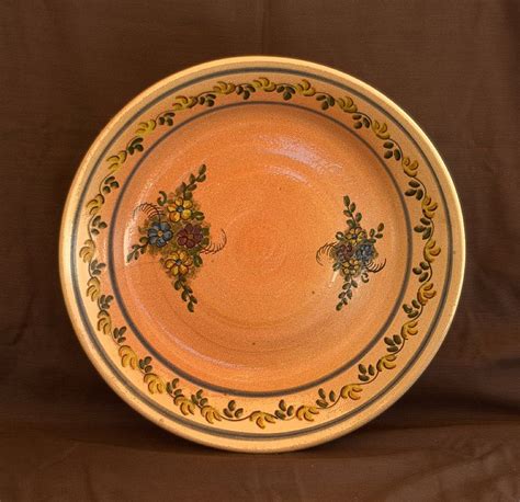 An Orange And Yellow Plate With Flowers On The Rim Is Sitting On A