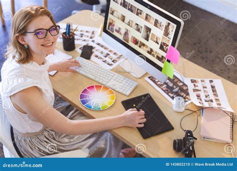 Female Graphic Designer Working On Graphic Tablet At Desk In Office