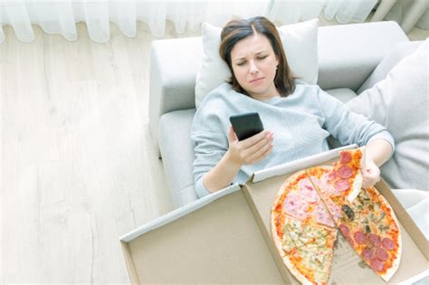 Femme Triste Mangeant Une Pizza Et Tenant Un Téléphone Couché Sur Le