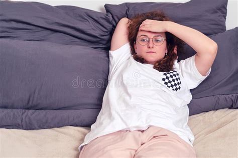 Red Haired Woman With Curly Hair Lies On The Bed Cute Girl In A White T Shirt On A Beige Bed