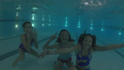 Underwater Shot Of Girls Submerging In Swimming Pool And Waving Stock