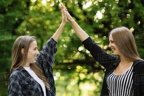 Two Young Female Friends High Fiving In Park Stock Photo Dissolve