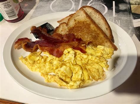 2 Scrambled Eggs Bacon And Wheat Toast With Cranberry Juice Food