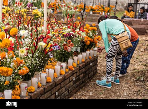 Los niños encienden velas a lo largo de una tumba decorada con maríguos