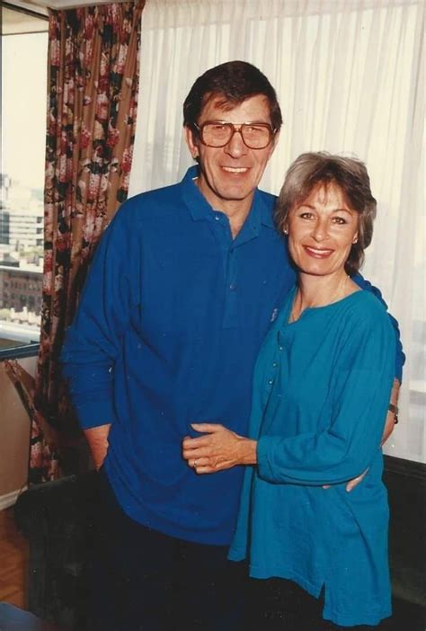 A Man And Woman Standing Next To Each Other In Front Of A Curtained Window