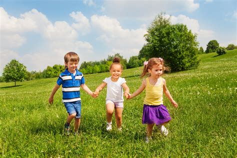 Three Happy Children Holding Hands And Playing Stock Photo Image