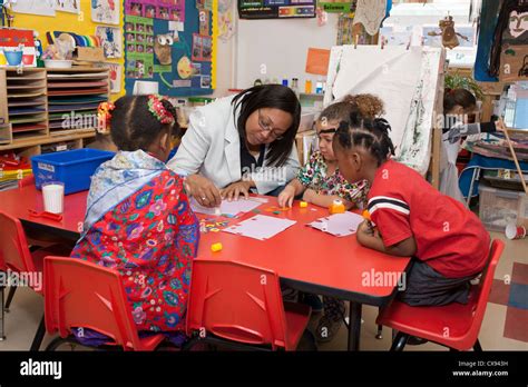 Female African American Preschool Teacher Drawing With Student Stock