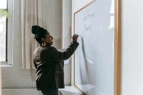 Cheerful Teacher Writing On Whiteboard In Classroom · Free Stock Photo