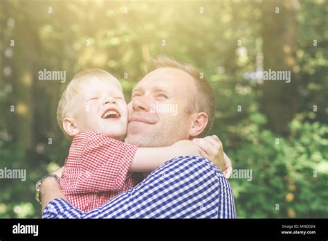 Father And Son Hugging Smiling And Looking At The Sun And Screwing Up