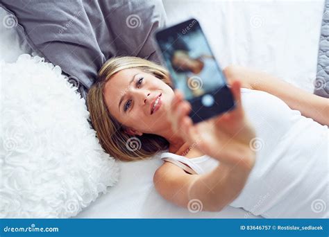 Young Woman Lying On The Bed And Making Selfie Photo Stock Image
