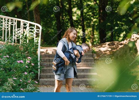 Caucasian Mom Circles Her Little Son Holding Him In Her Arms On A Summer Walk In The Park