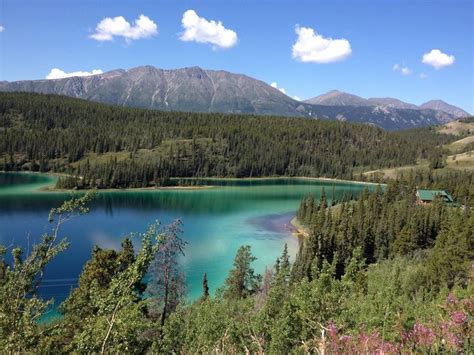 A Lake Surrounded By Trees And Mountains With Blue Water In The