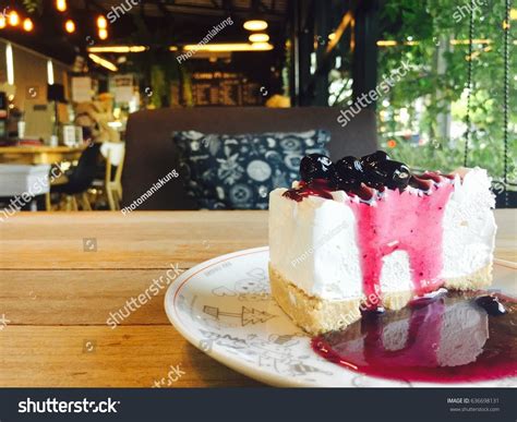 However, sadly i've noticed that quite a. A plate of blue blurry cheese cake in the cafe coffee shop atmosphere, on wooden table with ...