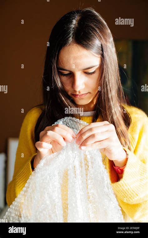 Teen girl popping bubbles in a bubble wrap at home to relax and fun